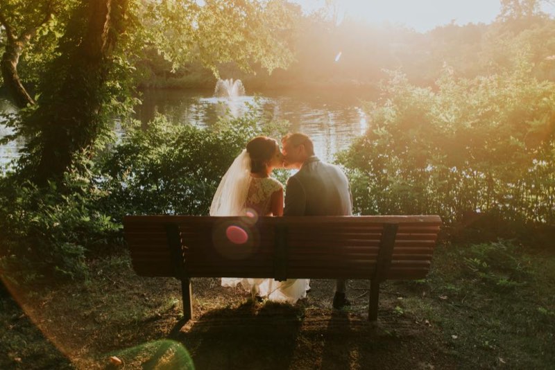 A couple kissing on a bench by a lake in golden evening light