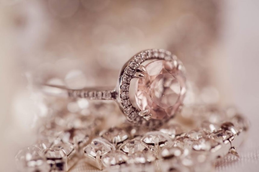 A pale pink oval stone in a halo of small diamonds on a pavé band