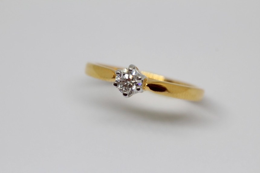 The finished ring: a round diamond held by six white gold claws on a slim polished yellow gold band