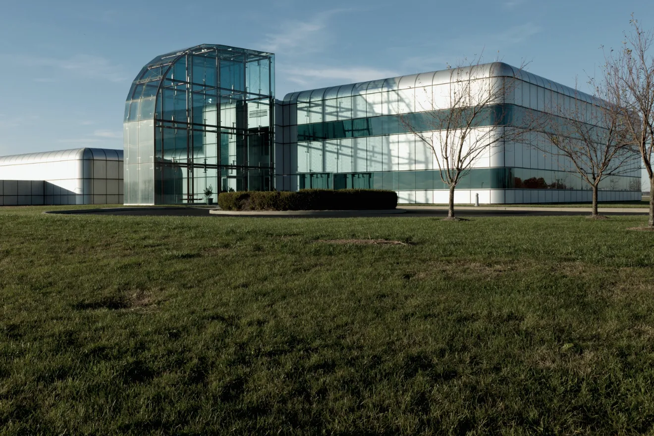 A low glass-and-steel building on a wide lawn, with a two-storey glass entrance hall.