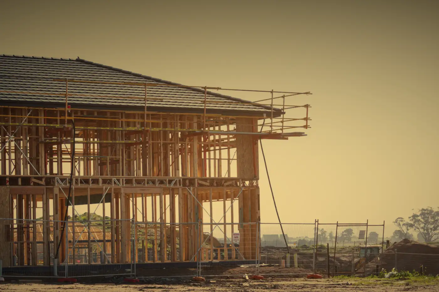 A two-story house frame with the roof on, wrapped in scaffolding.