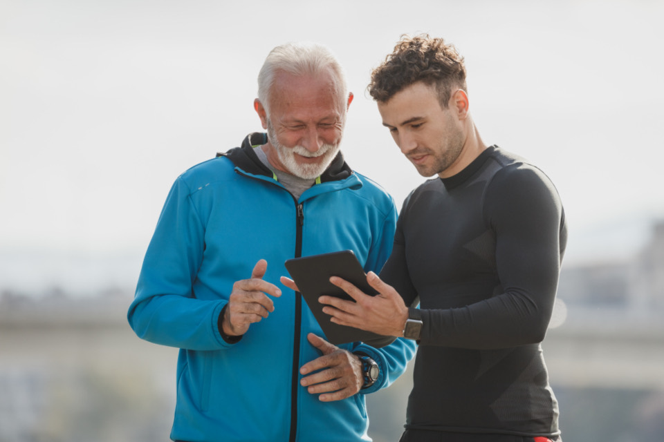 Coach Jordan and an older member smiling at a training plan on a tablet