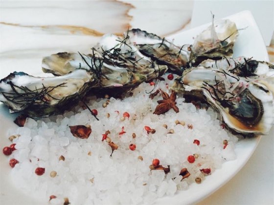 Six oysters on the half shell laid on a bed of rock salt with pink peppercorns and star anise.