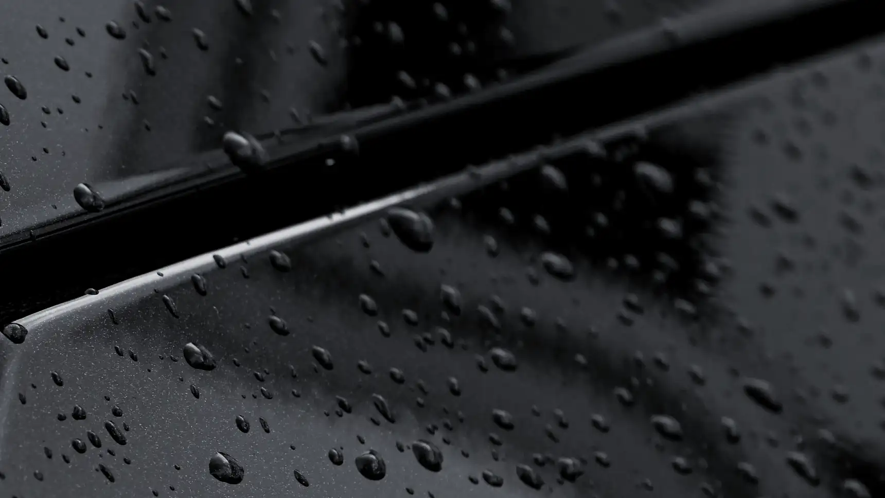 Rain beading across a black hood and fender after a ceramic coat