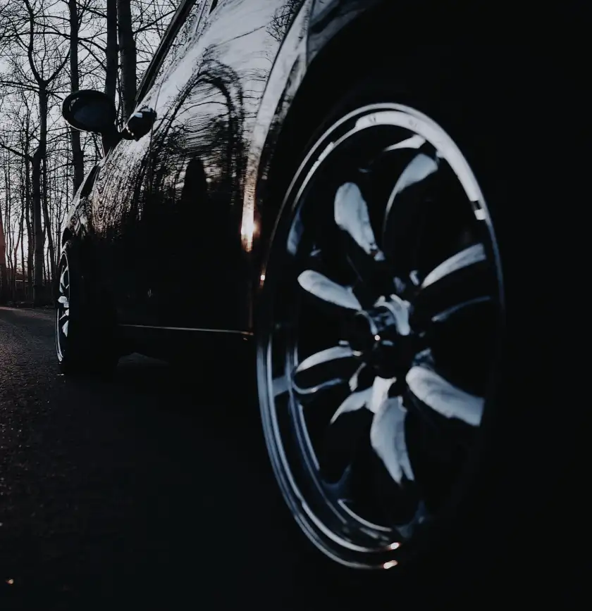 A gloss-black wheel and arch on a dark SUV at sunset