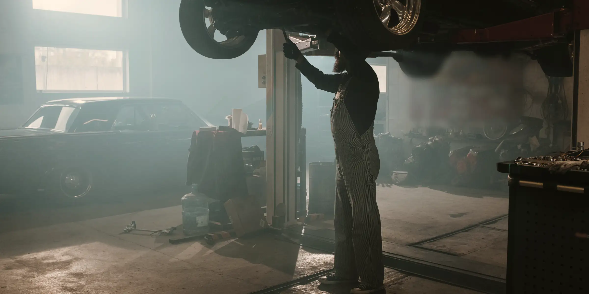 Inside the shop: two cars raised on lifts under bright work lights.