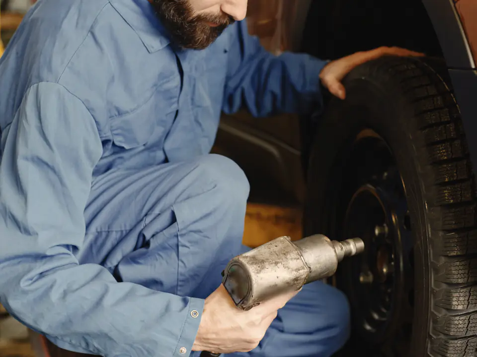 A technician fits a wheel and tire back onto a car.
