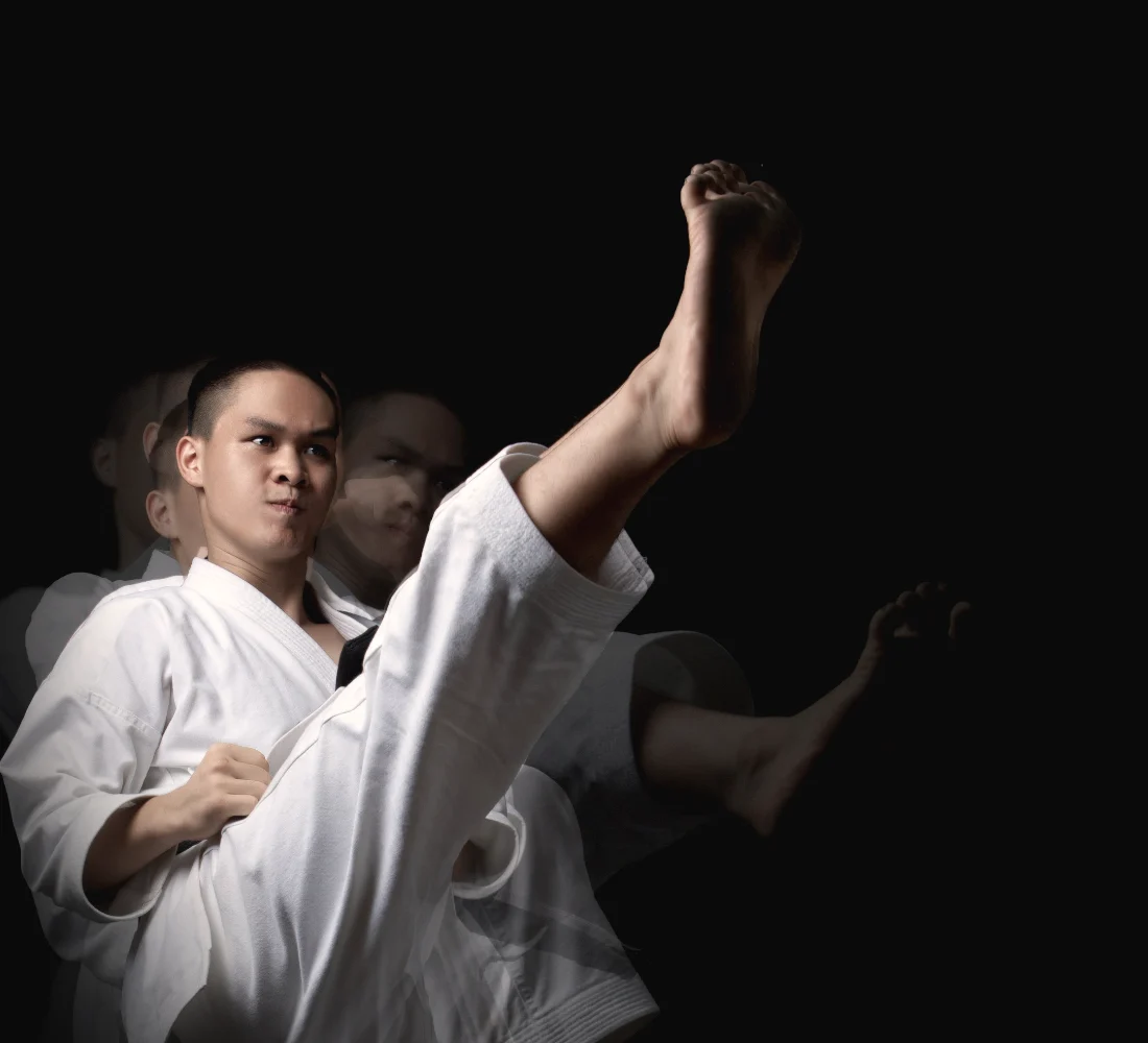 A karateka throws a high front kick, caught three times in one frame as his leg rises