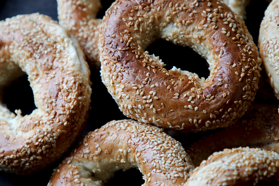 A pile of sesame bagels with golden, blistered crusts.