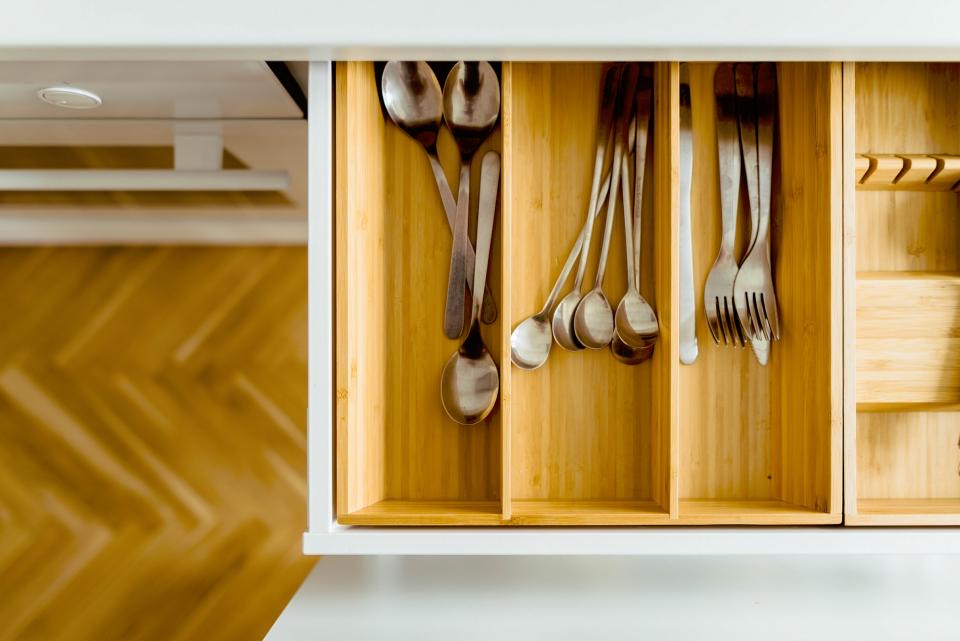 Open kitchen drawer with bamboo dividers holding spoons, forks and serving utensils