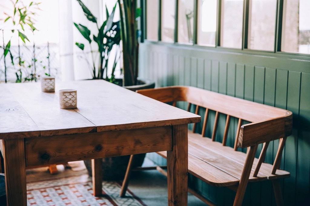 The finished table with labels on its plank top, a square leg and the wooden bench beside it