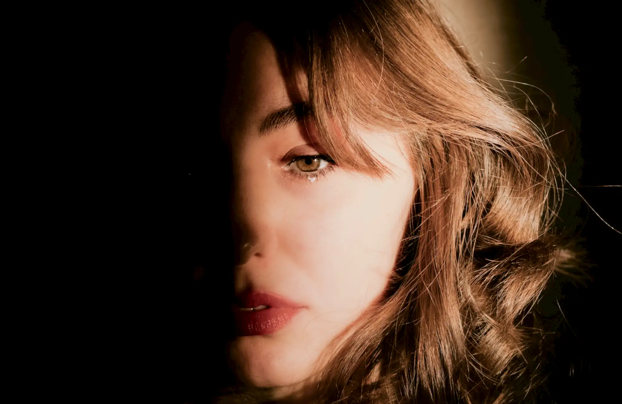 A client with a soft copper bob, half her face in shadow, and a red lip.