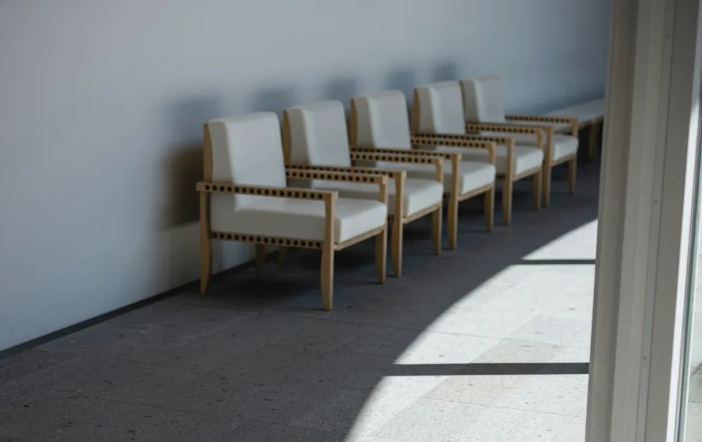 A row of white armchairs along a wall in soft daylight